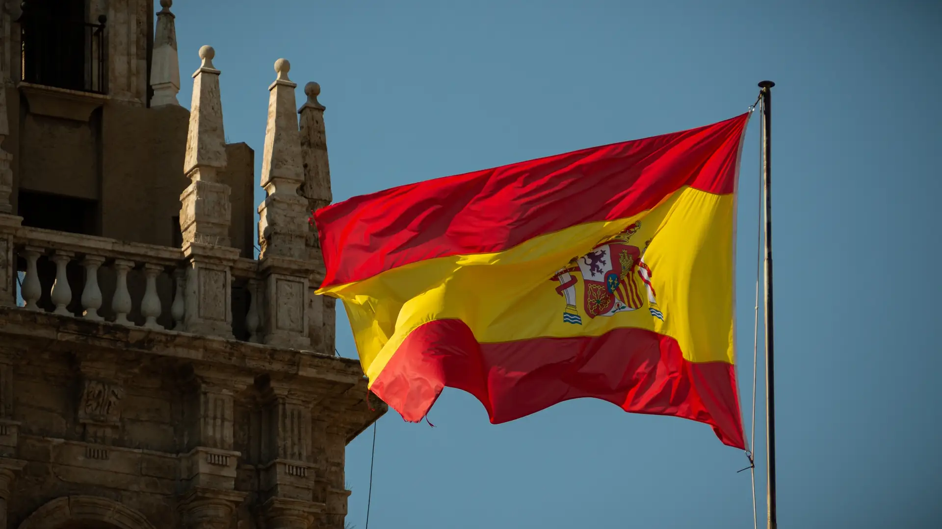Bandeira da Espanha tremulando ao lado de um edifício histórico
